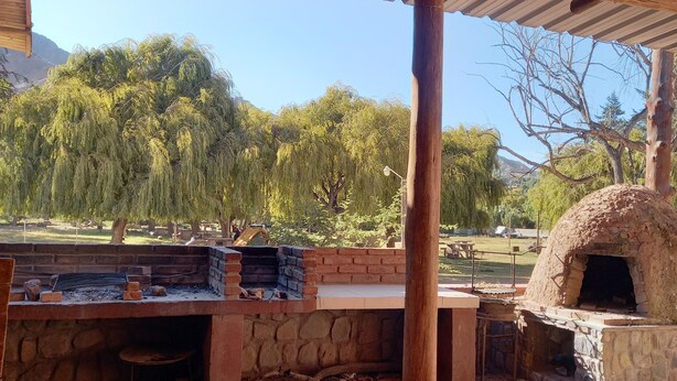 An outdoor patio with a brick fire pit, a stone oven, and a covered seating area. - Complejo Turístico Cruz Mendoza (Tilcara)