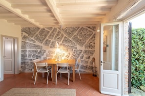 A dining area with a wooden table and chairs, a patterned wall, and a door leading outside. - Unique Villa with Infinity Pool in the heart of Chianti (Greve in Chianti)