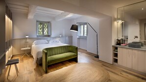 Une chambre à coucher moderne avec un lit, un canapé vert, une table de chevet, une lampe et un grand miroir.