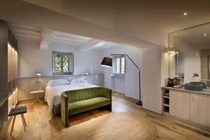 A modern bedroom with a bed, a green sofa, a bedside table, a lamp, and a large mirror. - Unique Villa with Infinity Pool in the heart of Chianti (Greve in Chianti)