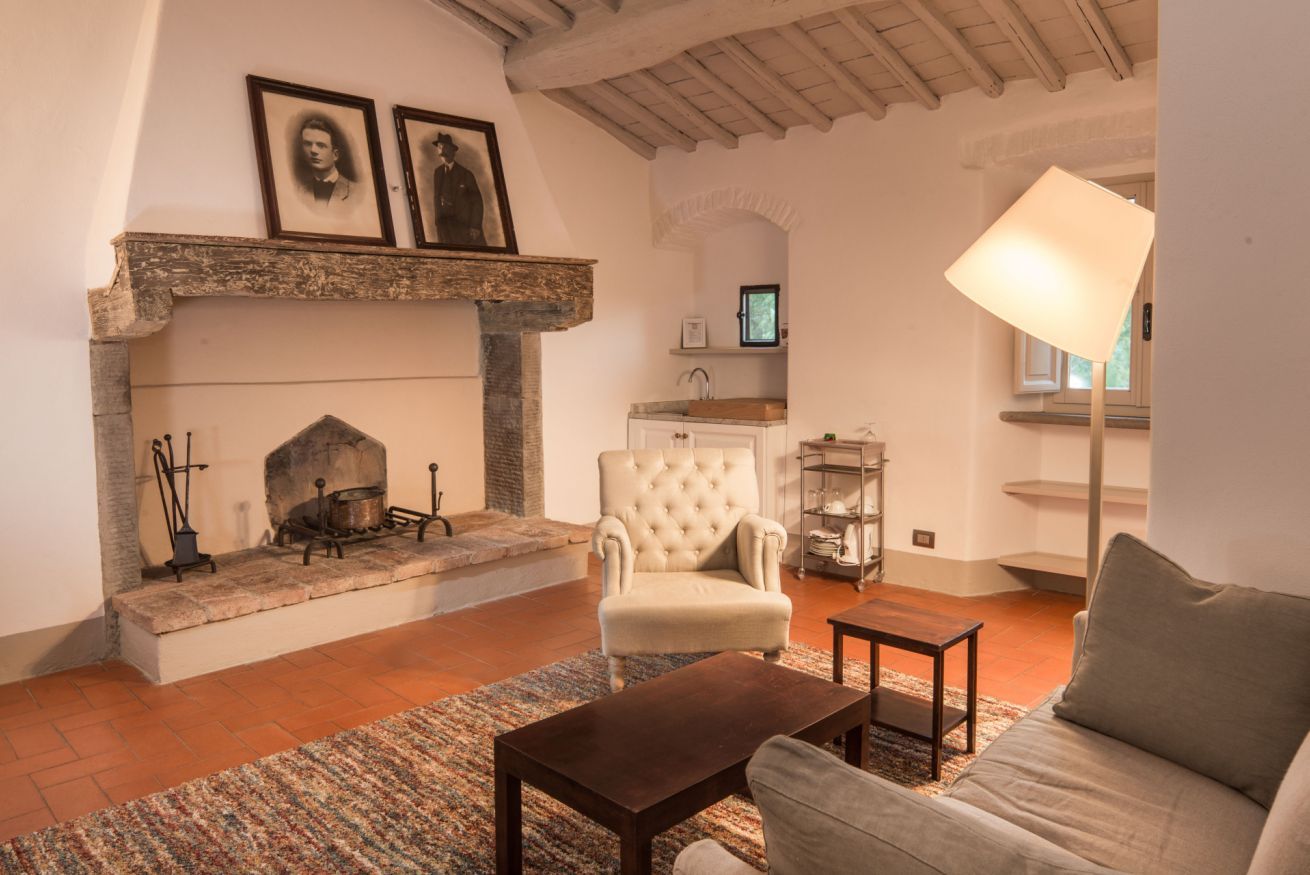 Una sala de estar con chimenea, un sofá, un sillón y una mesa de centro.