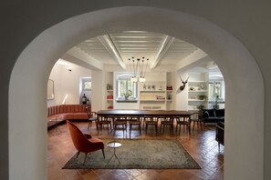 Un espace repas avec une grande table et des chaises, une chaise rouge et un tapis.