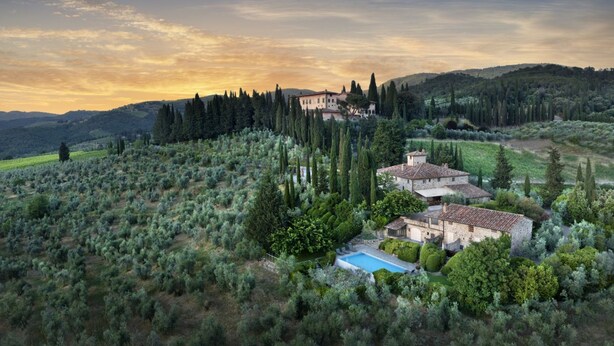 Une villa avec piscine, entourée d’oliviers et de cyprès, située sur une colline.