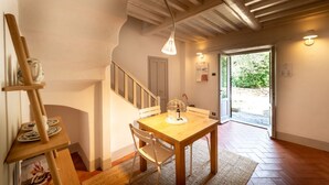 Un coin repas avec une table et des chaises en bois, un luminaire suspendu et un escalier menant à une autre pièce.