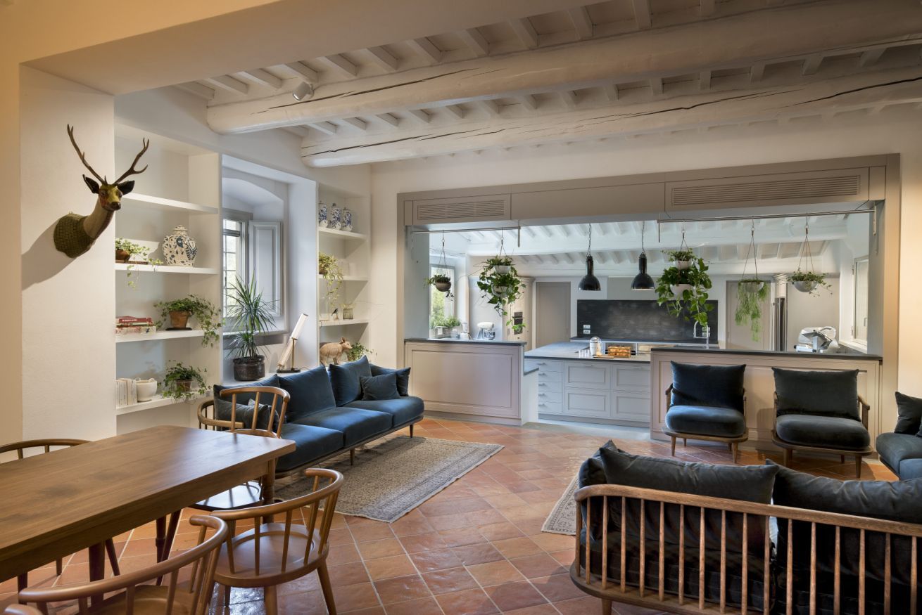 A spacious living area with a dining table, sofas, and a kitchen in the background.