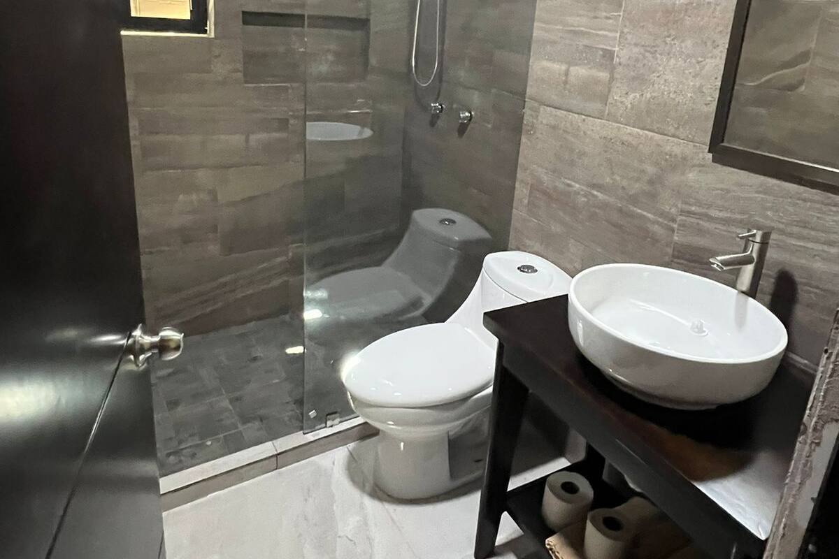 A modern bathroom with a glass-enclosed shower, a toilet, and a vanity with two sinks.