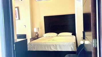 Un dormitorio con una cama, una mesita de noche, una lámpara y una silla.