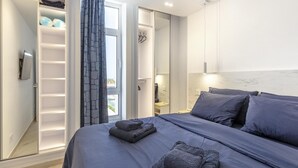 Un dormitorio moderno con una cama grande, un vestidor y vistas al exterior.