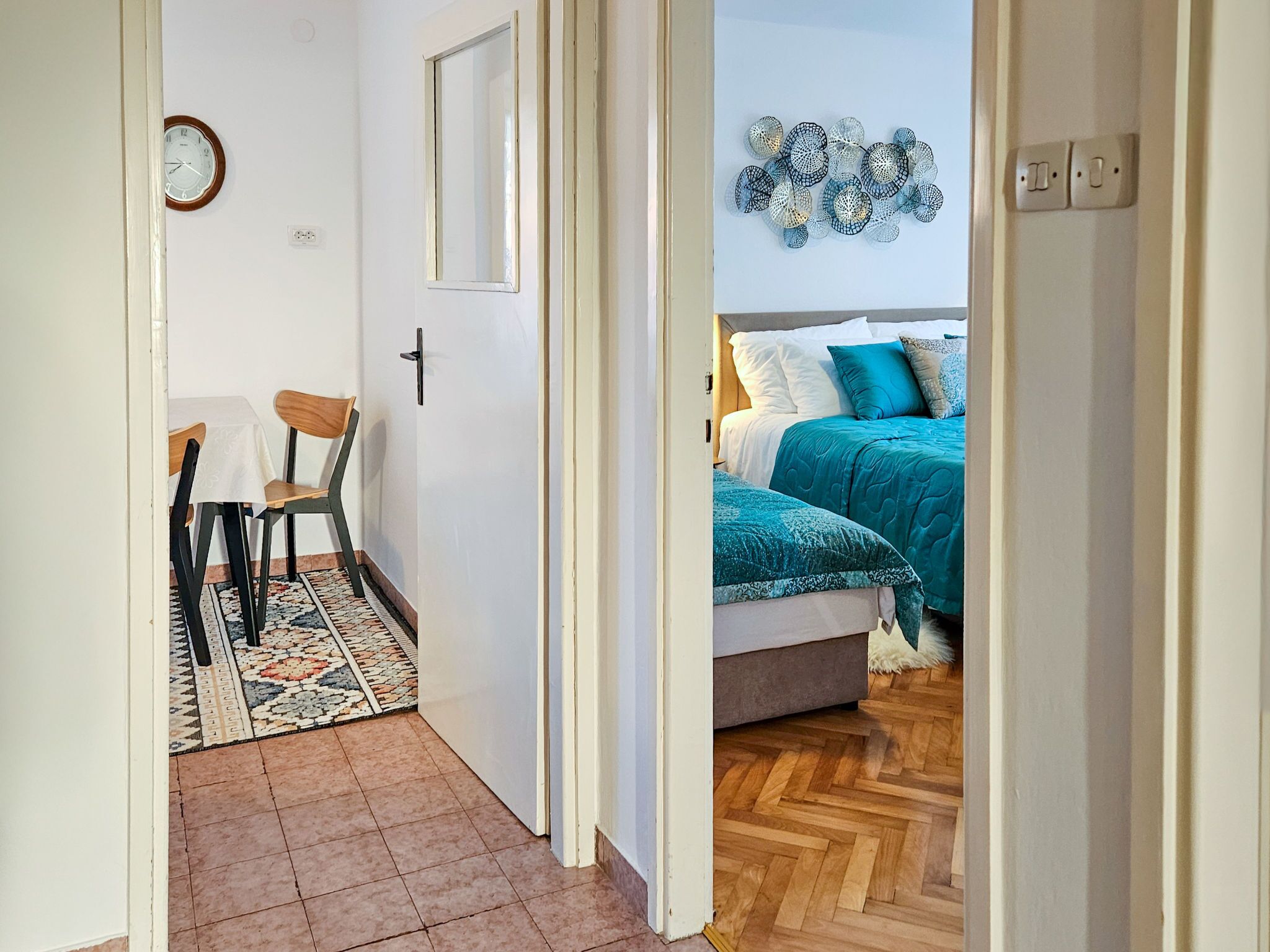 Ein Zimmer mit Bett, Stuhl, Tisch und Wanduhr.