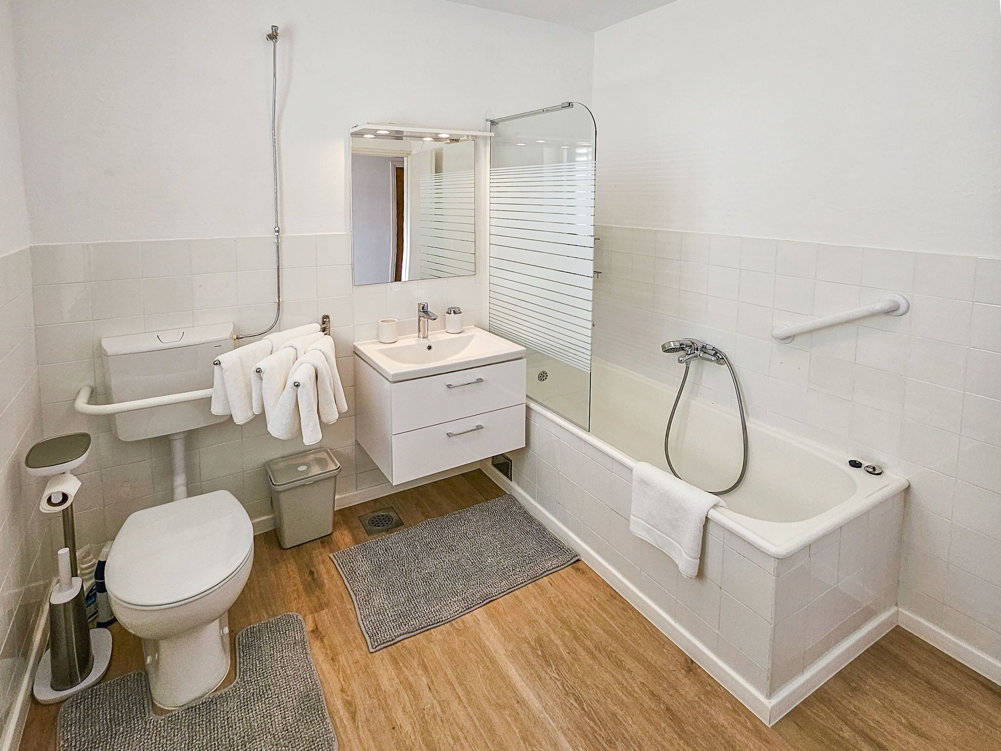 A modern bathroom with a toilet, sink, mirror, and shower.