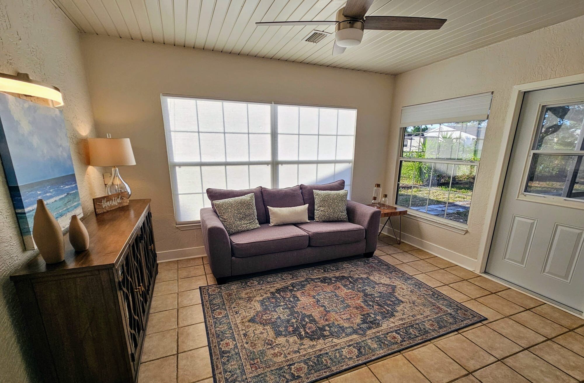 A living room with a large window, a ceiling fan, and a view of the outdoors.
