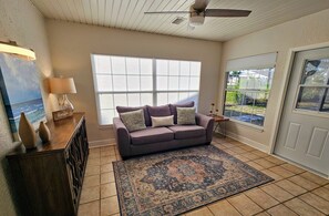 A living room with a large window, a ceiling fan, and a view of the outdoors.