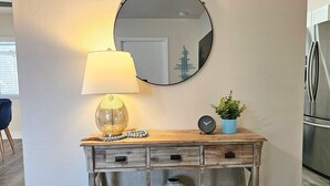 Una consola de madera con un espejo, una lámpara y elementos decorativos.