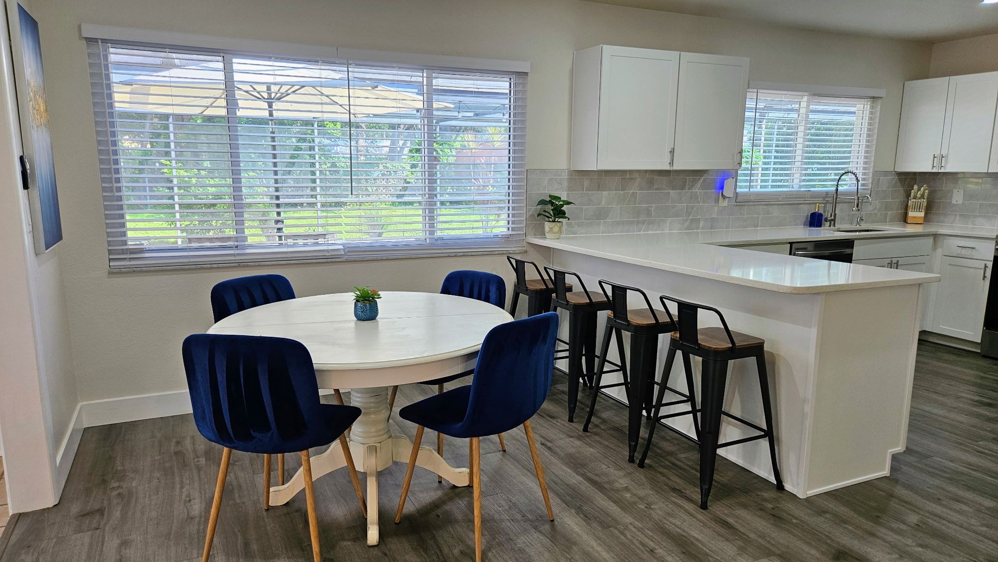 Una cocina moderna con una isla central, taburetes de bar y una mesa de comedor con sillas.
