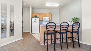 Eine moderne Küche mit Holzausstattung, einer Mikrowelle, einem Kühlschrank und einer Bar mit vier Sitzplätzen.