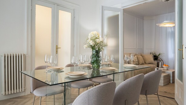 A modern dining area with a glass table, multiple chairs, and a vase of flowers. - Refined & Spacious 3-Bedroom Flat Near Cismigiu, Balcony with Boulevard Views (Bucharest)