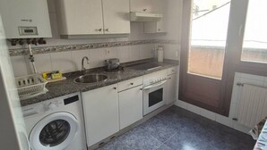 Een praktische keuken met een ingebouwde wasmachine, een spoelbak en een raam.
