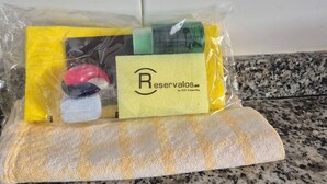 Een plastic zak met een gele envelop, een rood voorwerp, een groen voorwerp en een zwart voorwerp op een gestructureerd oppervlak.