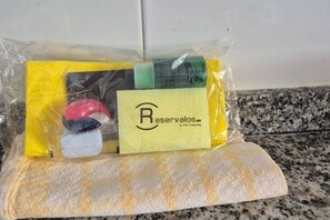 Un sac en plastique contenant une enveloppe jaune, un objet rouge, un objet vert et un objet noir, le tout posé sur une surface texturée.