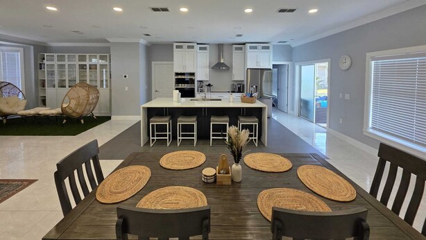 A modern kitchen with white cabinets, a central island, and recessed ceiling lights.