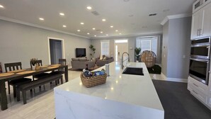 A modern kitchen with a central island, dark flooring, and built-in appliances.