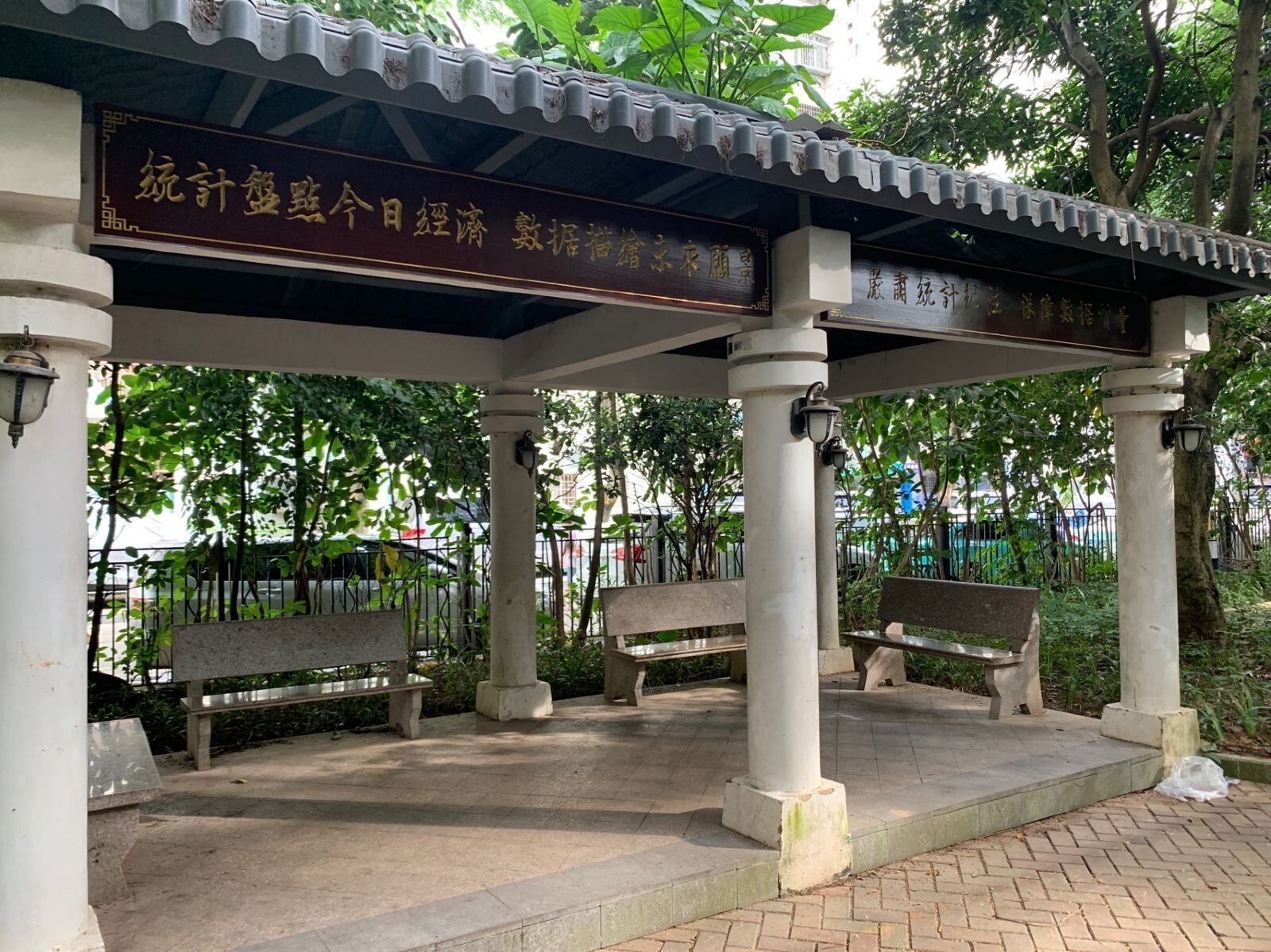A covered pavilion with benches and a signboard.