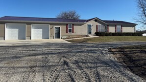 A single-story house with a garage, a front door, and a small porch. - Quiet. Relaxing. 4-bedroom House with AC, Jetted Tub and WiFi.  (Snover)