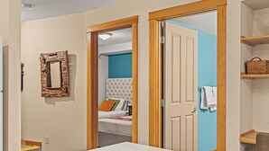 Une chambre à coucher avec un lit, un miroir et une porte donnant sur une autre pièce.