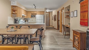 Une cuisine moderne avec des meubles en bois, un îlot central et un coin repas comprenant une table et des chaises en bois.