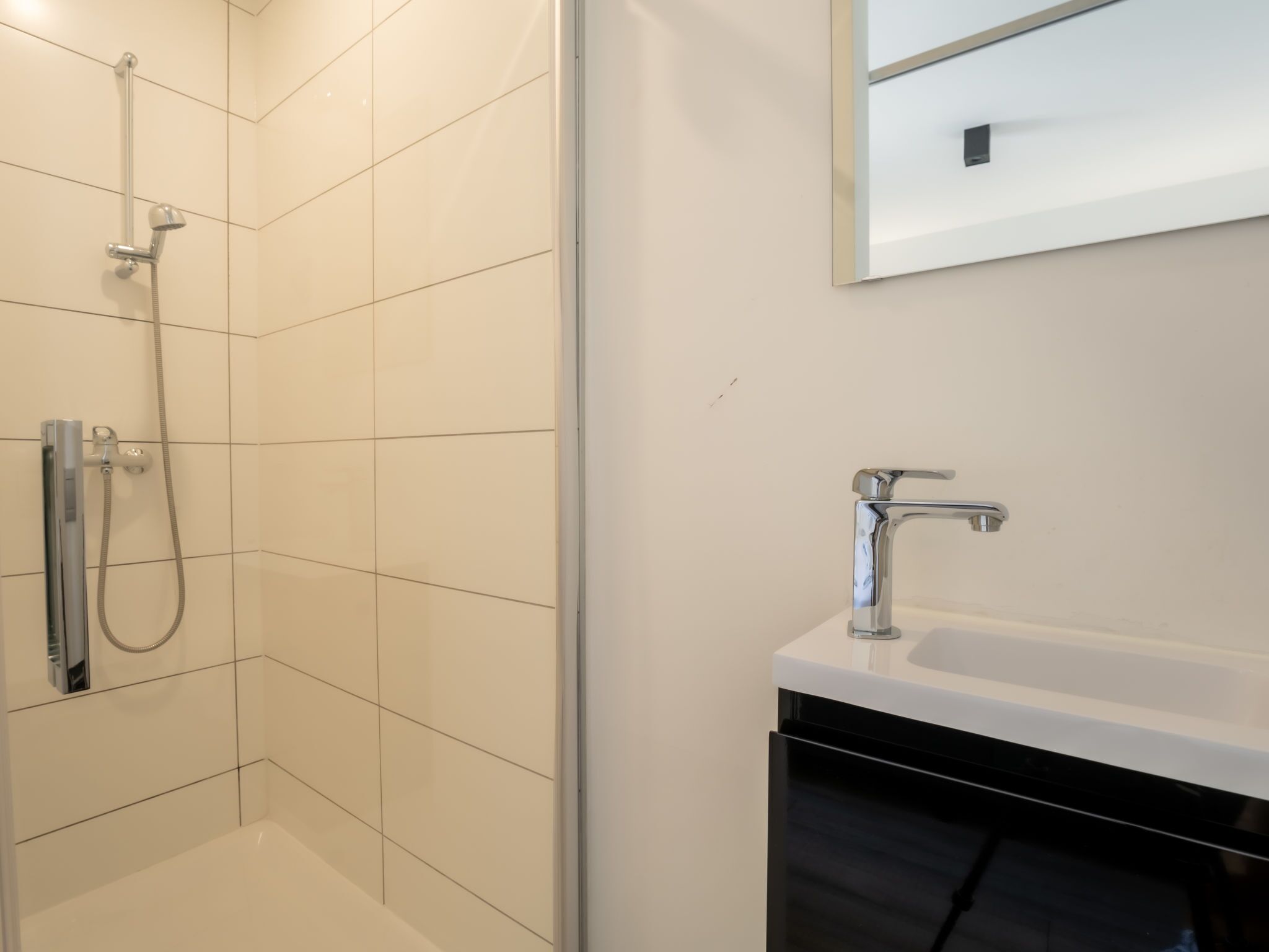 Une salle de bain moderne avec une douche, un lavabo et un miroir.