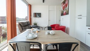 A modern dining area with a wooden table, red and black chairs, and a view of the city through large windows.