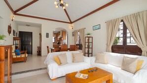 A spacious living room with a white sofa, wooden coffee table, and a dining area with wooden furniture. - Lanzahost "Casa Patricio" (Costa Teguise)