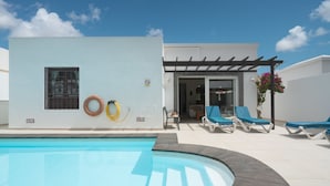 A swimming pool with a curved edge, a pergola, and lounge chairs. - Lanzahost "Casa Patricio" (Costa Teguise)