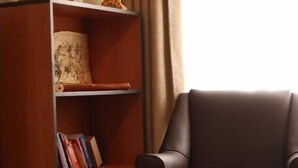 Una sala de estar con un sill ón de cuero marrón, una estantería de madera con libros y una pequeña mesa redonda.