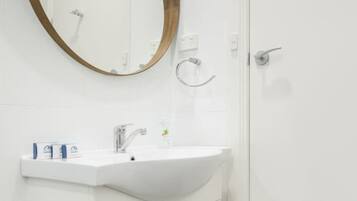 A bathroom with a white sink, a round mirror with a wooden frame, and a white door.