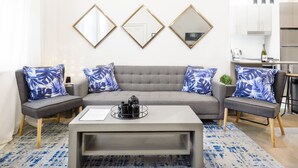 A modern living room with a grey sofa, matching armchairs, and a coffee table. There are three wall-mounted mirrors above the sofa. - Huge Designer Studio Next to Lovely Park (North Sydney)