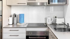 Una cocina moderna con electrodomésticos de acero inoxidable, microondas, tostadora y hervidor.