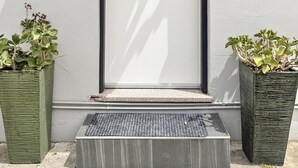 A white door with a black frame and the number 5 on it, flanked by two potted plants.