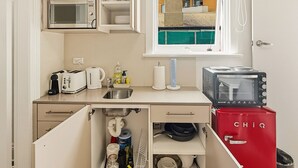 A compact kitchenette with a microwave, toaster, and small refrigerator.