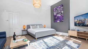 Una habitación de hotel moderna con una cama, un televisor, una mesita de centro y un cuadro en la pared.