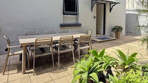 An outdoor patio area with a dining table and chairs, a small window, and potted plants. - Cute 1 bedroom with private courtyard garden (North Sydney)