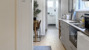 A modern kitchen with white cabinetry, a built-in oven, and a window with a view. - Cute 1 bedroom with private courtyard garden (North Sydney)