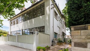A modern two-story building with large windows, a concrete pathway, and potted plants. - Sun Drenched Ground Floor Studio with Patio (North Sydney)
