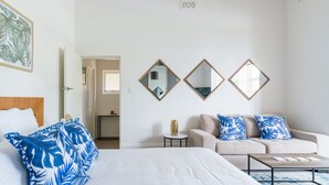 A hotel room with a bed, a sofa, a coffee table, and three wall mirrors. - Sun Drenched Ground Floor Studio with Patio (North Sydney)