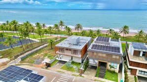 Propiedad costera con varias construcciones, paneles solares y vista al mar.