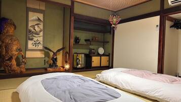 A traditional Japanese room with tatami mats, a shoji screen, a wooden statue, and a hanging decorative piece.