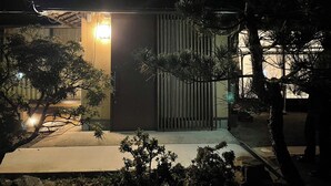 A modern building with a sloped roof, a visible entrance, and a small porch area. - Warouan (Nikko)