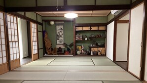 A traditional Japanese room with tatami flooring, sliding doors, and a shelf with various items. - Warouan (Nikko)