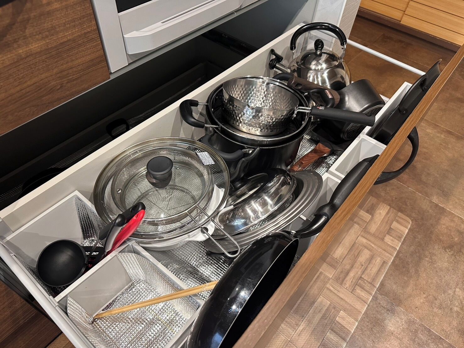 A kitchen with a built-in stove, a kettle, a frying pan, and a pot.