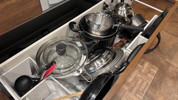 A kitchen with a built-in stove, a kettle, a frying pan, and a pot.
